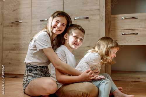 three children play at home. brother and sisters laugh and have fun. Homeliness is admiration and love. Family concept.