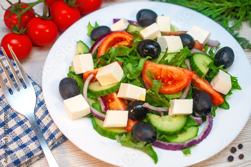Greek salad with tomatoes, cucumbers and feta cheese with olives on the table