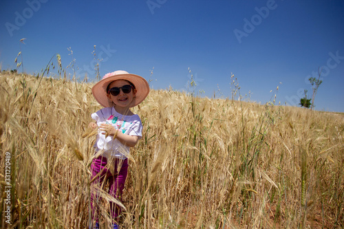 in the wheat field. little girl with a hat