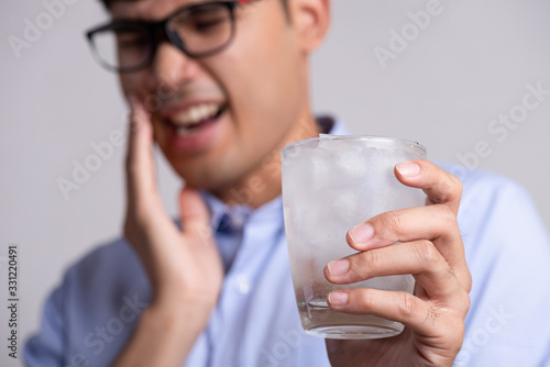 Принти на полотні Young man with sensitive teeth and hand holding glass of cold water with ice