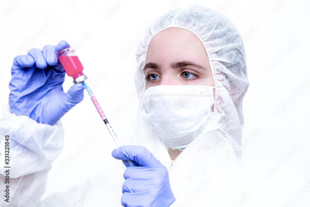 A virologist from viruses in a protective suit and medical mask dials pink medicine into a syringe. A masked female nurse with a syringe in her hand on a white background. A virologist from viruses in a protective suit and medical mask dials pink medicine into a syringe. A masked female nurse with a syringe in her hand on a white background.