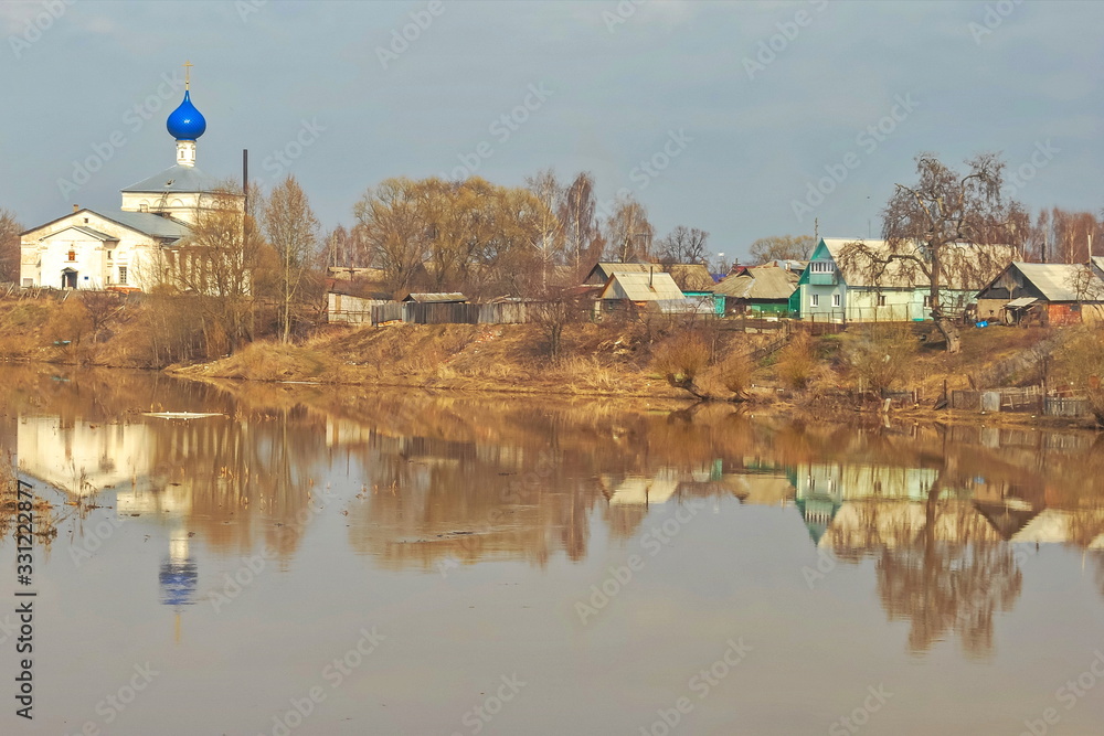 Village with  strange church on  banks of  spring river