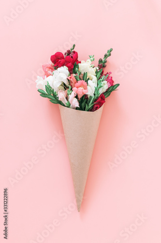 Leinwand Poster Roses bouquet in cone on pink background, flat lay, top view.