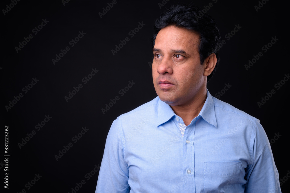 Fototapeta premium Mature handsome Indian businessman against black background