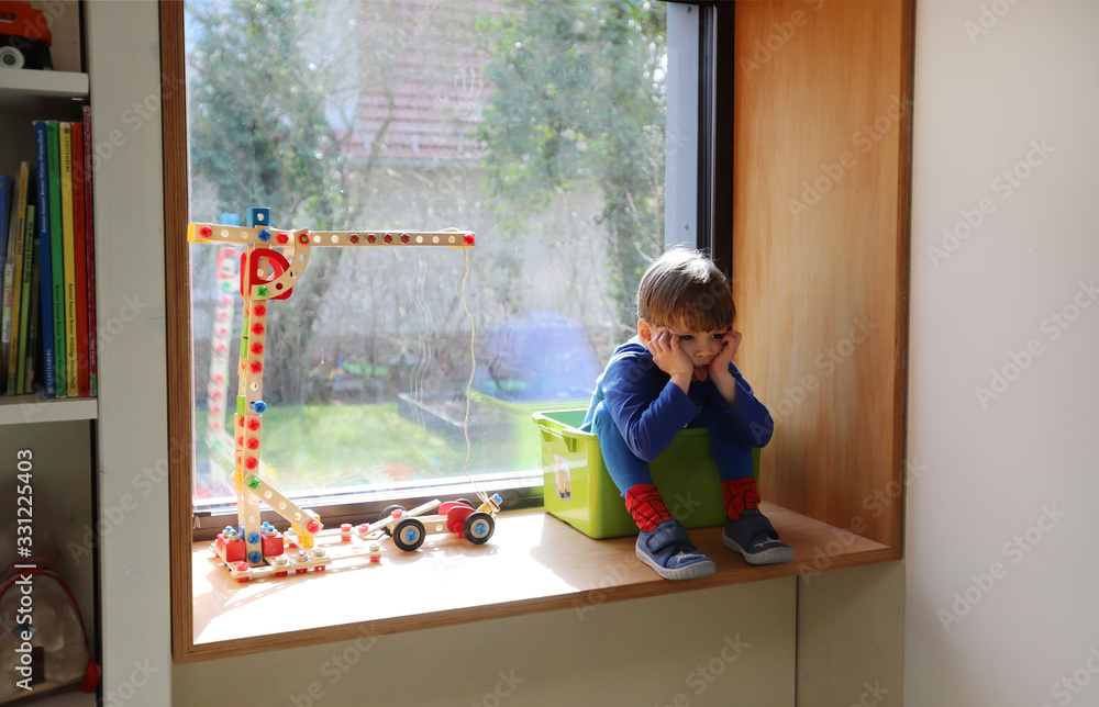 Ein vierjähriger Junge sitzt gelangweilt in seinem Zimmer am 18.03.2020. - obrazy, fototapety, plakaty 