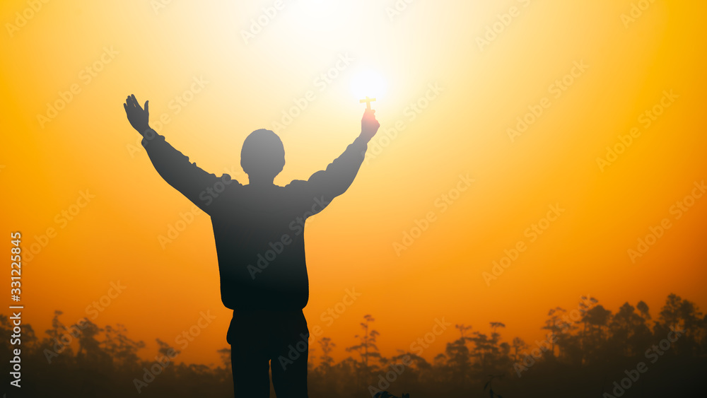 Man lift the Cross up to sky for praying and worship God at sunset background. christian silhouette concept.