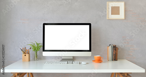 Workspace computer monitor with white blank screen putting on white working desk with books, coffee cup, potted plant, pencil holder, wireless keyboard and mouse. Orderly workplace concept. © Prathankarnpap