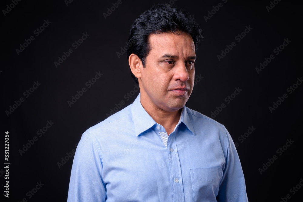 Obraz premium Mature handsome Indian businessman against black background