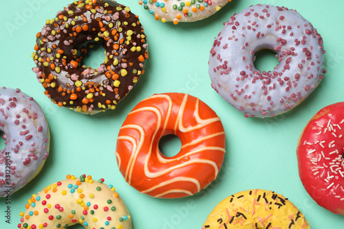 Delicious glazed donuts on turquoise background, flat lay