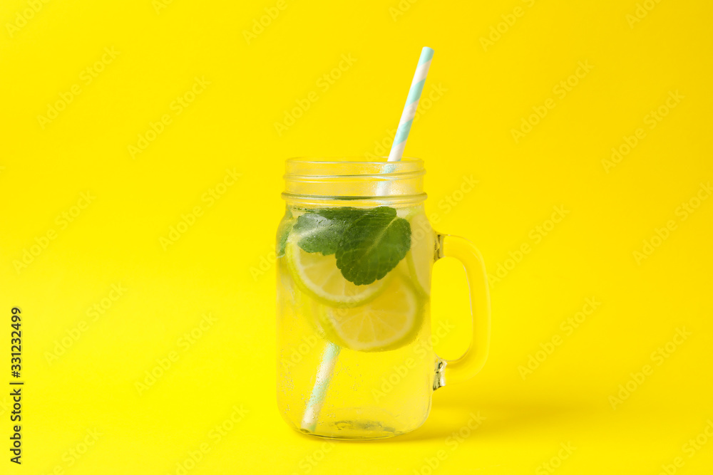 Glass jar with lemonade on yellow background. Fresh drink