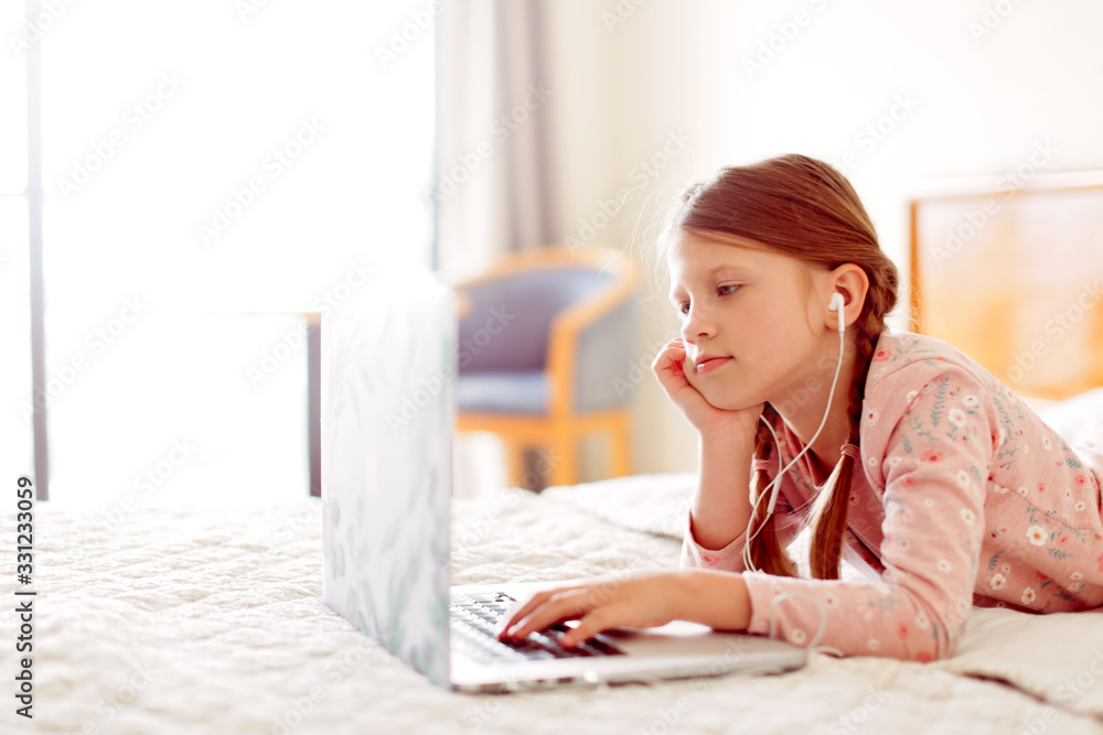 child in headphones does homework laptop in bed child in headphones does homework laptop in bed
