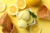 Ice cream, lemon and waffles on yellow background, top view
