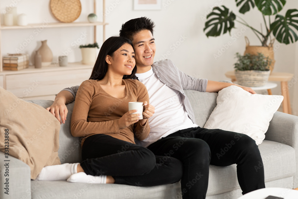 Filipino couple resting at home and watching tv - obrazy, fototapety, plakaty 