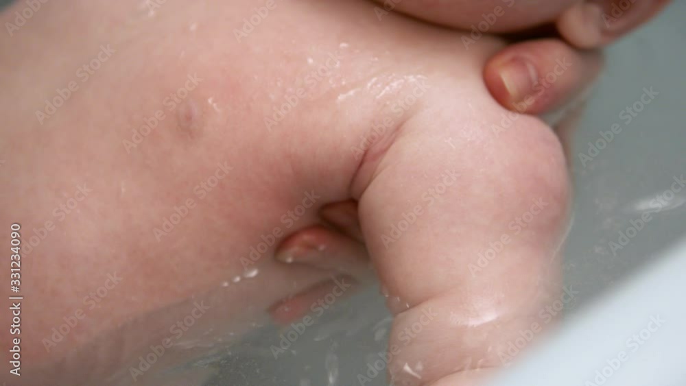 Newborn baby bath. Mother holding a baby to float in warm water. Selective soft focus, slow motion Newborn baby bath. Mother holding a baby to float in warm water. Selective soft focus, slow motion