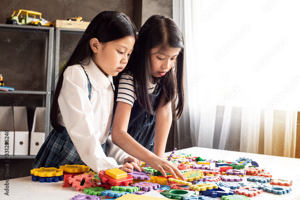 Fototapeta premium Two little girl playing colorful blocks on desk with interested feeling.at home studio.blurry light around