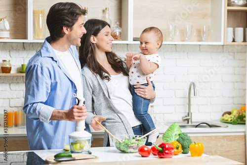 Happy family of three cooking together at kitchen