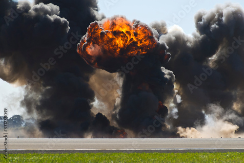 Firey explosion with thick black smoke on an airport runway.