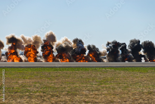Multiple firey explosions with thick black smoke on an airport runway.