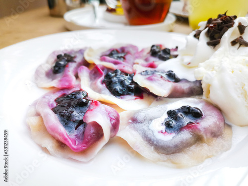 delicious sweet polish dumplings stuffed with blueberries jam and blueberries for toppings served with vanilla ice cream and Whipped cream in white plate