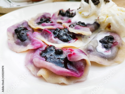 delicious sweet polish dumplings stuffed with blueberries jam and blueberries for toppings served with vanilla ice cream and Whipped cream in white plate