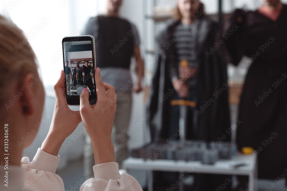 selective focus of girl taking photo of men in fairy costumes on smartphones