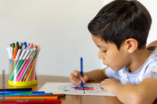 Close up of boy painting a mandala with his colored markers