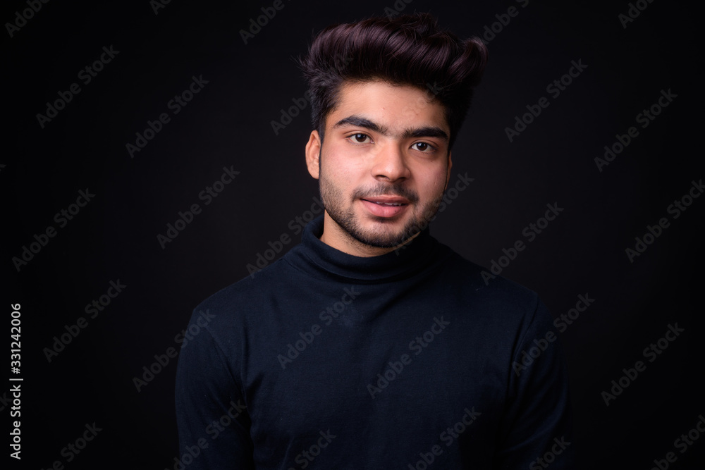 Fototapeta premium Young handsome Indian man against black background