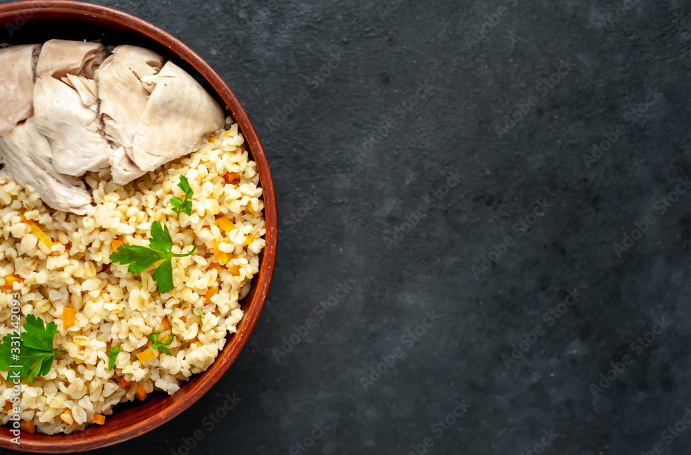 Bulgur with vegetables, chicken fillet on a stone background with copy space for your text. Healthy food