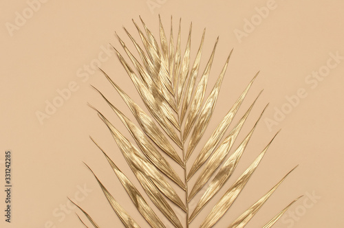 Gold colored tropical palm leaves on beige background flat lay top view copy space. Creative summer background with tropical leaves. Golden background  minimal nature concept