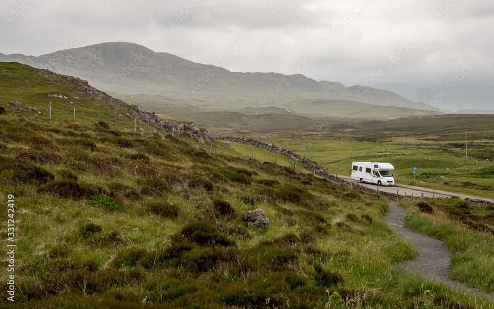 Fototapeta premium Motorhome touring in the Scottish Highlands. A view over the Highlands of Scotland with an RV parked up in a layby along the North Coast 500 route.