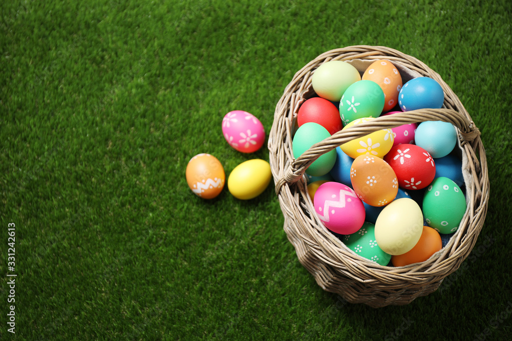 Colorful Easter eggs in basket on green grass, above view. Space for text Colorful Easter eggs in basket on green grass, above view. Space for text
