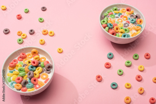 bright colorful breakfast cereal with milk in bowls on pink background