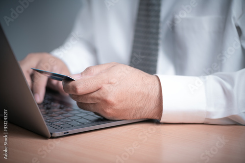 Businessman hands holding credit card and using laptop.