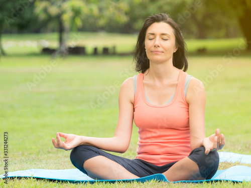 European women sitting, arms stretching, meditation and relaxing during the morning hours by yoga in an outdoor park