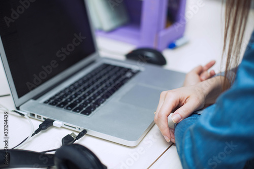 person works at home at the computer monitor close up. young woman programmer sitting at a laptop at office workplace. company employee of a computer close up. stay and study remotely at home