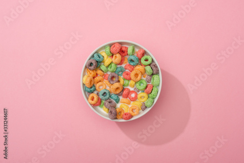 top view of bright colorful breakfast cereal in bowl on pink background photo