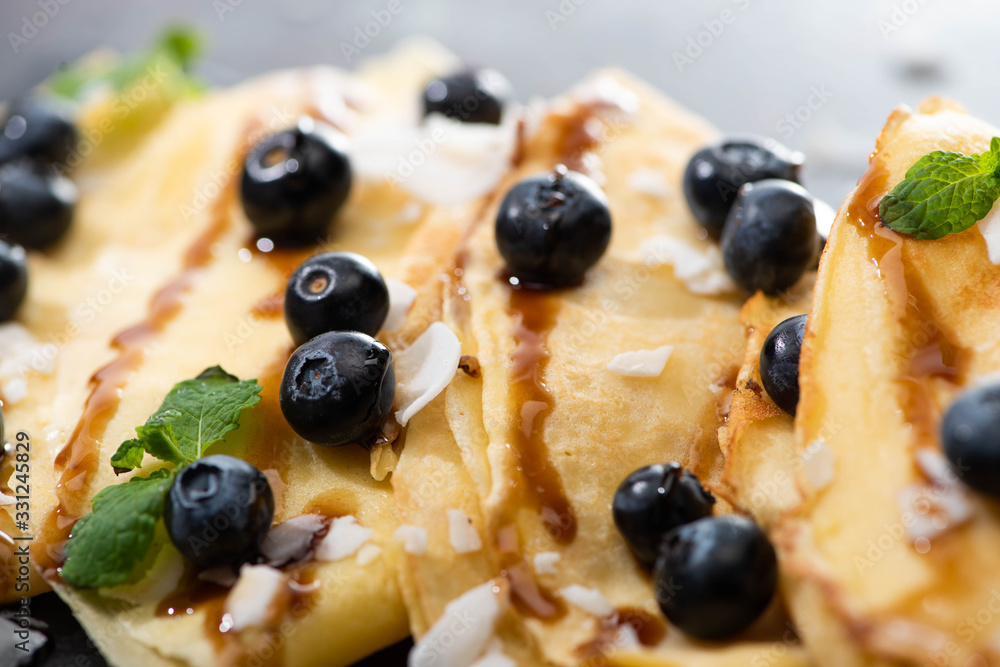 close up view of tasty crepes with blueberries, mint and coconut flakes close up view of tasty crepes with blueberries, mint and coconut flakes