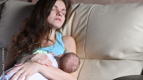 Young beautiful mother breastfeeds a baby and sleeps from fatigue
