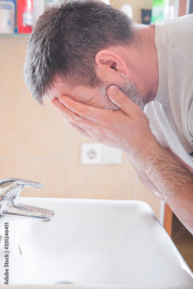 Obraz premium Man Washing Face In Bathroom Sink