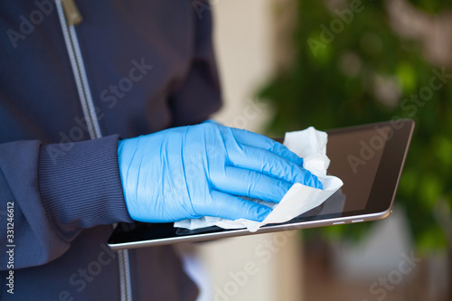 Fotografie man hands in gloves disinfecting tablet computer screen, eliminate germs coronav