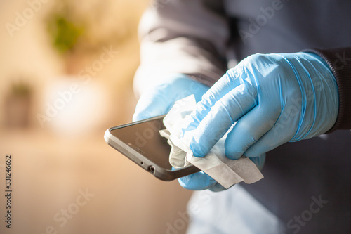 Photography man hands in gloves disinfecting smartphone, eliminating germs coronavirus bacte