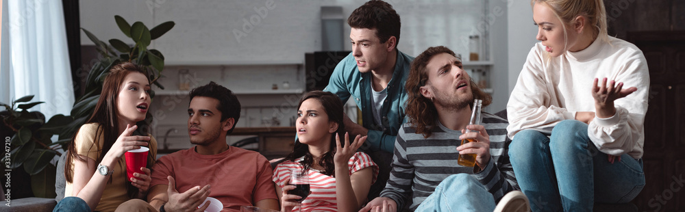 panoramic shot of excited friends talking and gesturing while sitting at home panoramic shot of excited friends talking and gesturing while sitting at home