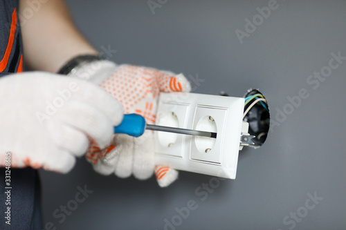 Fotografi Repairman in gloves fixing socket with screwdriver