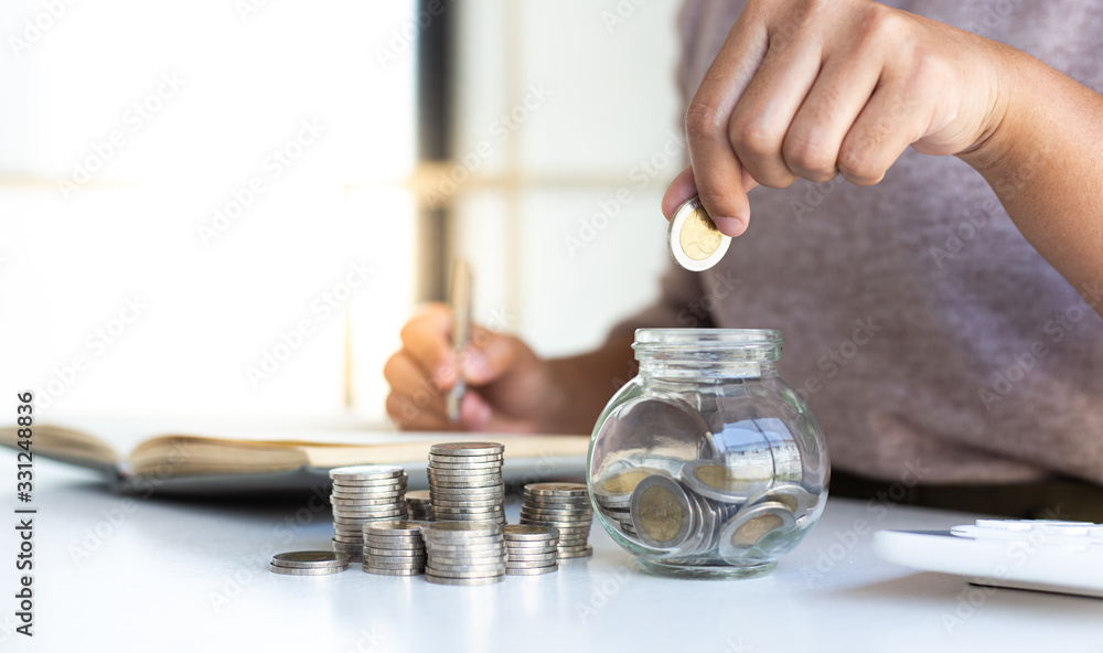 The businessman's hand holds the money in the piggy bank for saving money for future use, saving money for finance accounting concept.