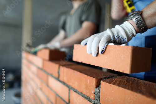 Two workers making red brick wall at construction site © megaflopp