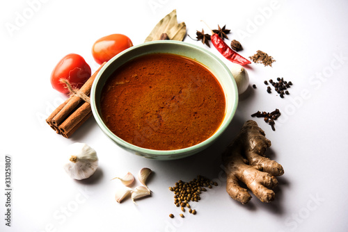 North Indian basic spicy Curry or masala for vegetables or chicken or mutton recipe shown with ingredients, served in a bowl. selective focus homemade, restaurant, hot, oil, dark, red, indian, india, 