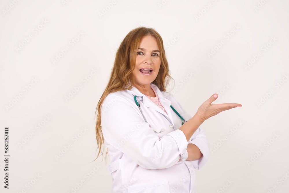 Positive glad doctor female says: wow how exciting it is, has amazed expression, shows something on blank space with open hand. Advertisement concept. Positive glad doctor female says: wow how exciting it is, has amazed expression, shows something on blank space with open hand. Advertisement concept.