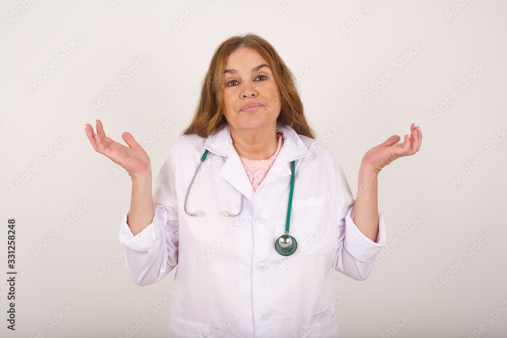 Puzzled and clueless young doctor woman with arms out, shrugging her shoulders, saying: who cares, so what, I don't know. Negative human emotions, facial expressions, life perception and attitude Puzzled and clueless young doctor woman with arms out, shrugging her shoulders, saying: who cares, so what, I don't know. Negative human emotions, facial expressions, life perception and attitude
