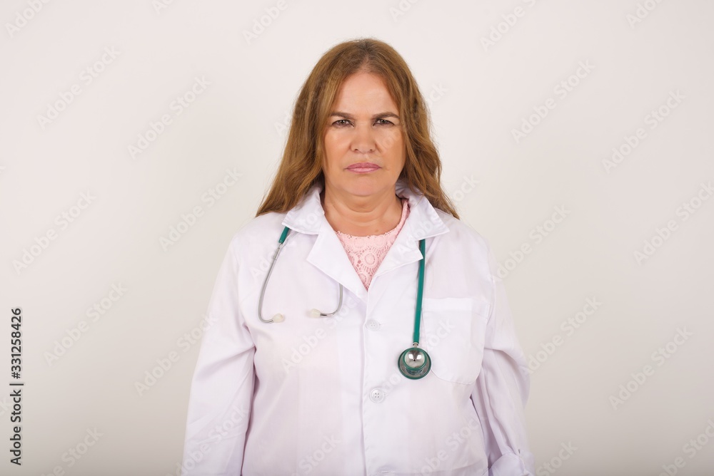 Portrait of outraged young doctor woman wearing medical uniform, frowning her eyebrows being displeased with something. Scowling pretty female isolated over grey. Portrait of outraged young doctor woman wearing medical uniform, frowning her eyebrows being displeased with something. Scowling pretty female isolated over grey.