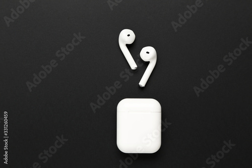 White wireless earphones on black background